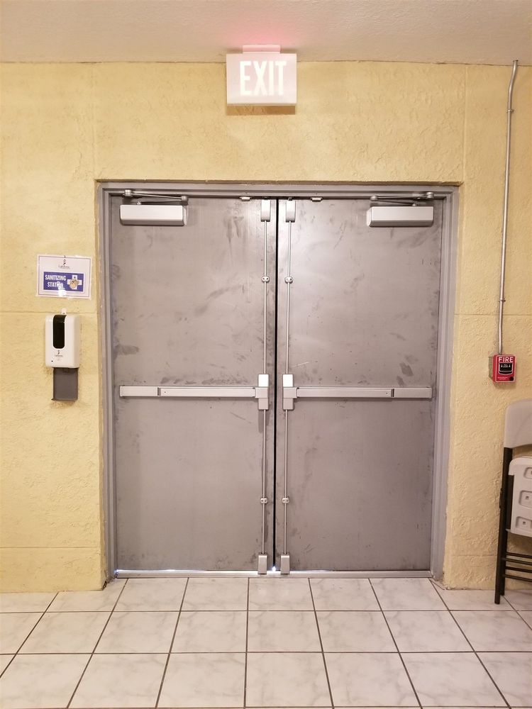 Pair of hollow metal doors with panic bars, closers and exit sign in a corridor