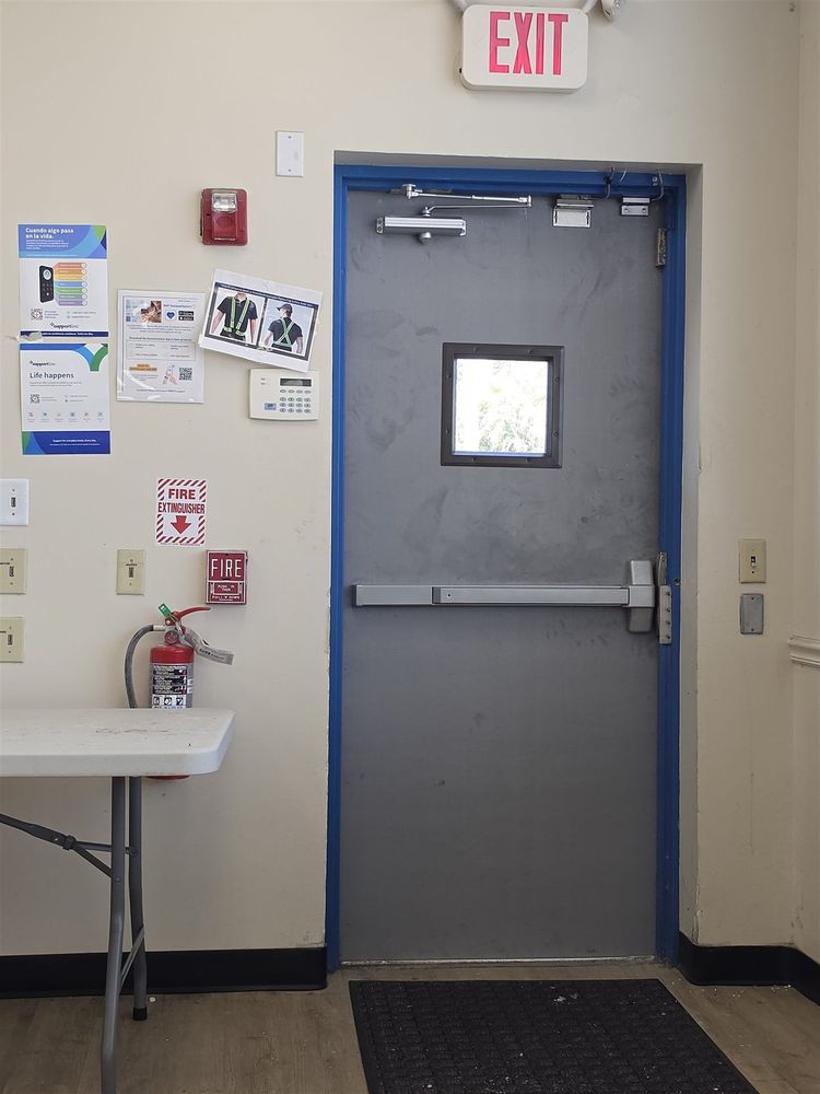 Steel exit door with vision lite and panic bar in a blue frame under an exit sign